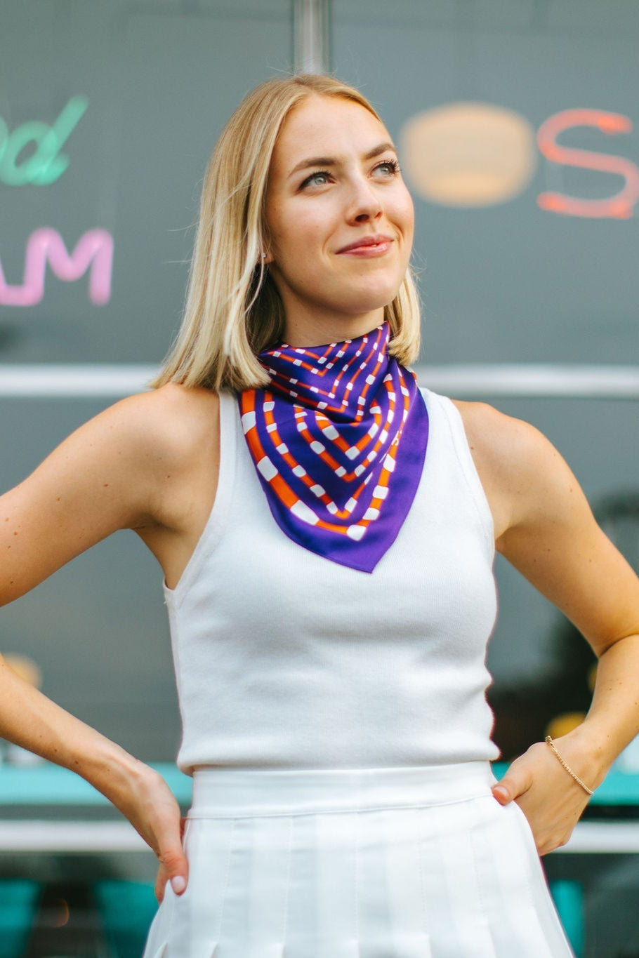 Woman wearing a colorful scarf in front of a building with signs for 'Angel Food' and 'Soda'.